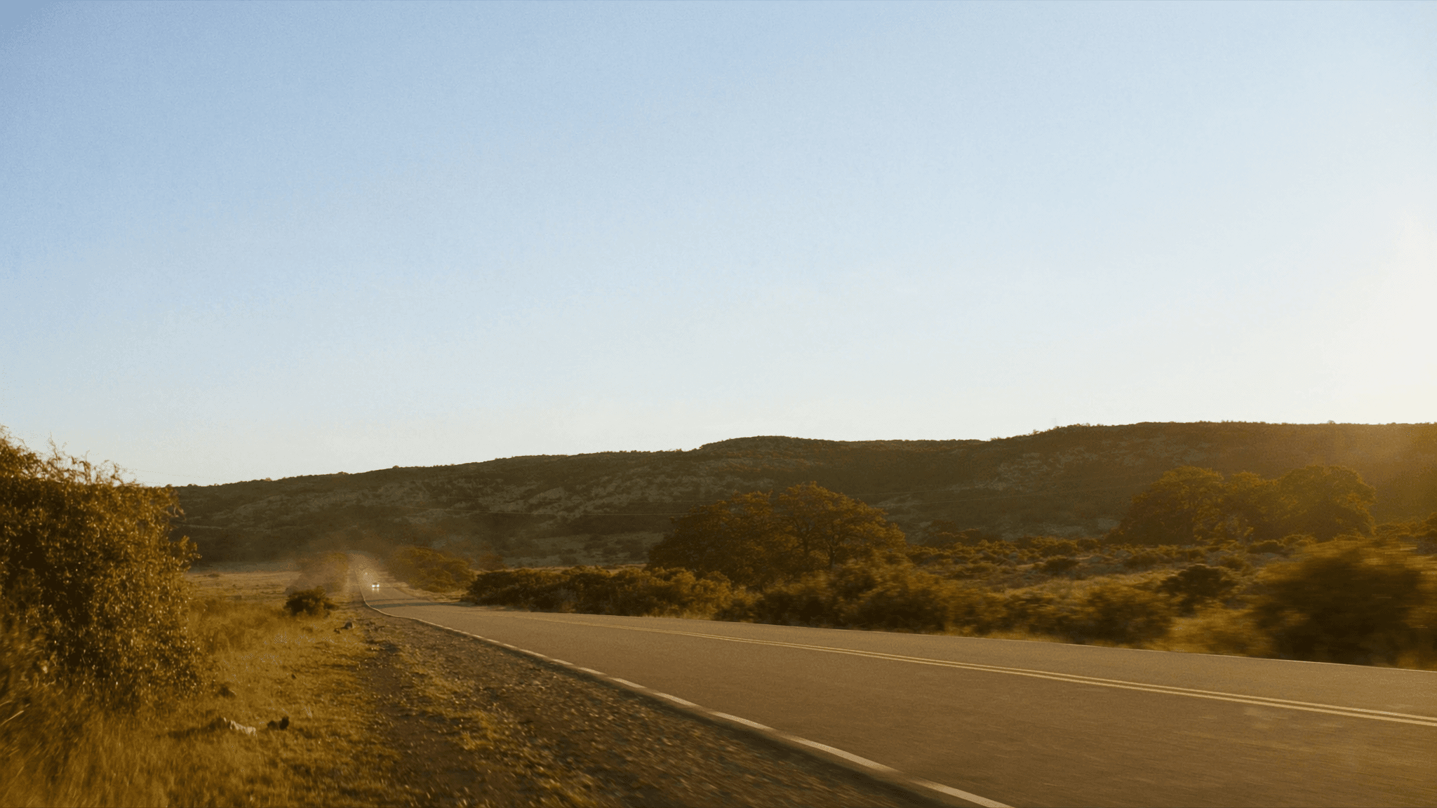 Two-lane road through Texas Hill Country at golden hour